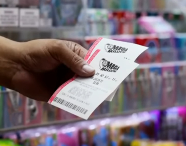 A hand holding two Mega Millions Lottery Tickets