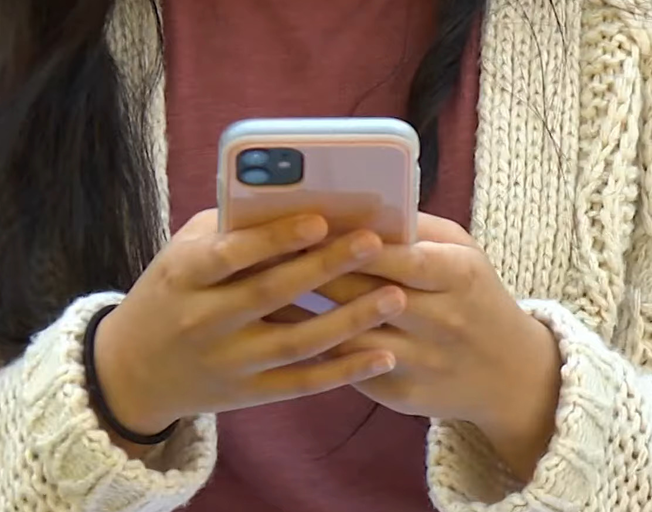 A person holding a smart phone while typing on it