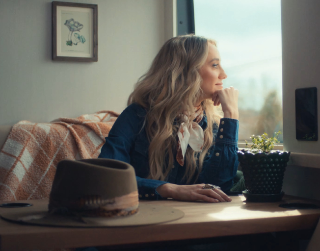 Lainey Wilson staring out the window of her tour bus